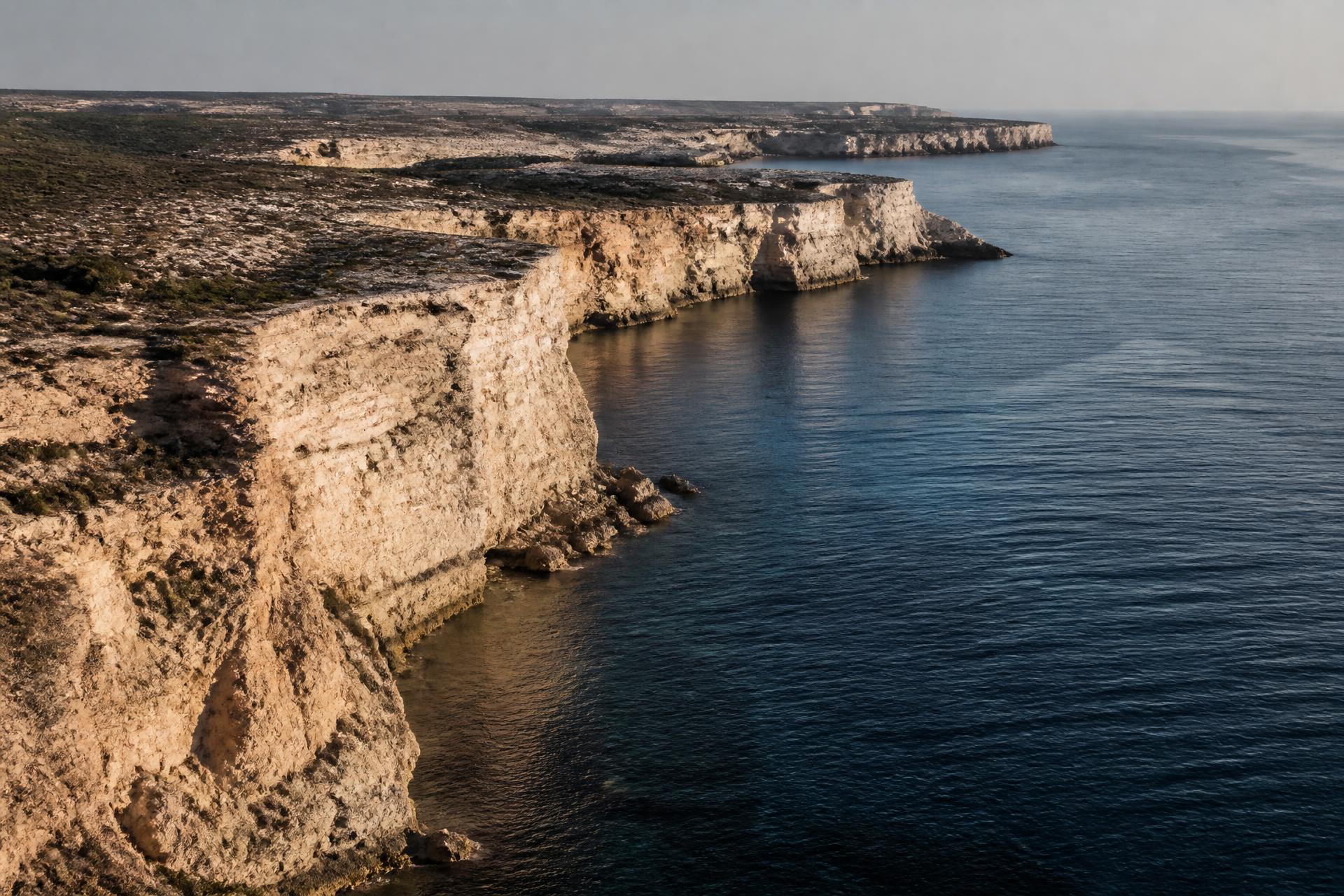 Limestone cliffs along the Cyprus coastline meeting the Mediterranean at low sun
